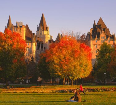 a group of people sitting in a field in front of a castle