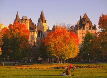 a group of people sitting in a field in front of a castle