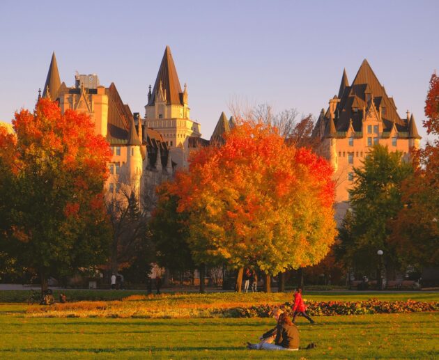 a group of people sitting in a field in front of a castle