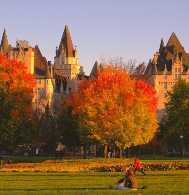 a group of people sitting in a field in front of a castle