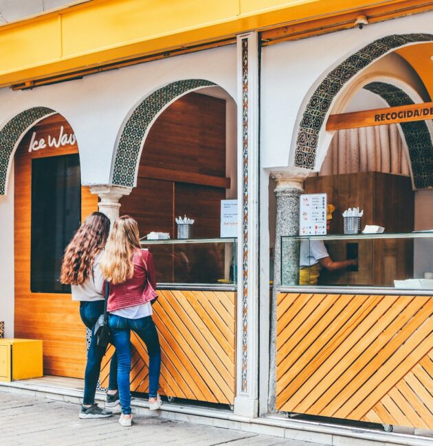 two woman standing in front of food stall