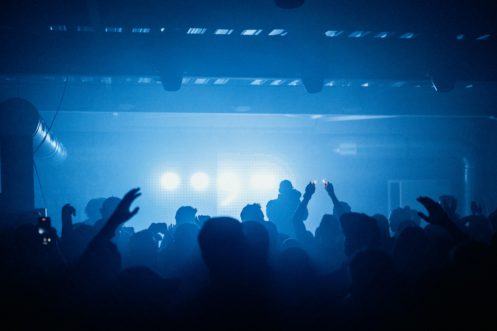 a crowd of people at a concert with their hands in the air