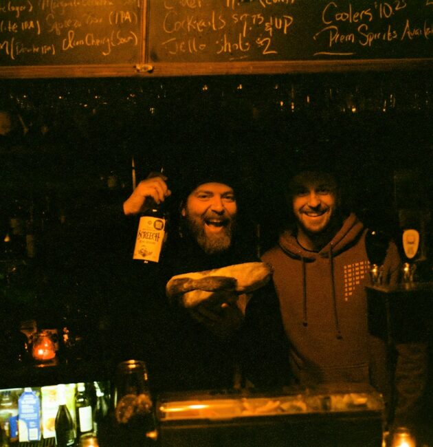 a couple of men standing next to each other at a bar