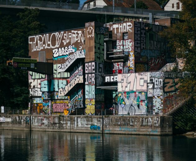 a body of water with a wall with graffiti on it