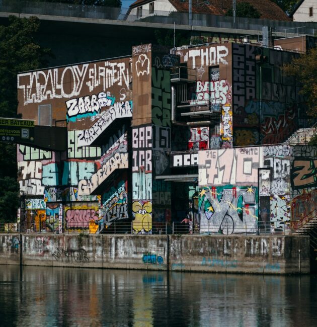 a body of water with a wall with graffiti on it