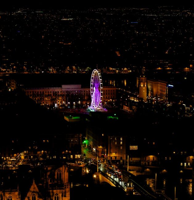 a city at night with a ferris wheel lit up